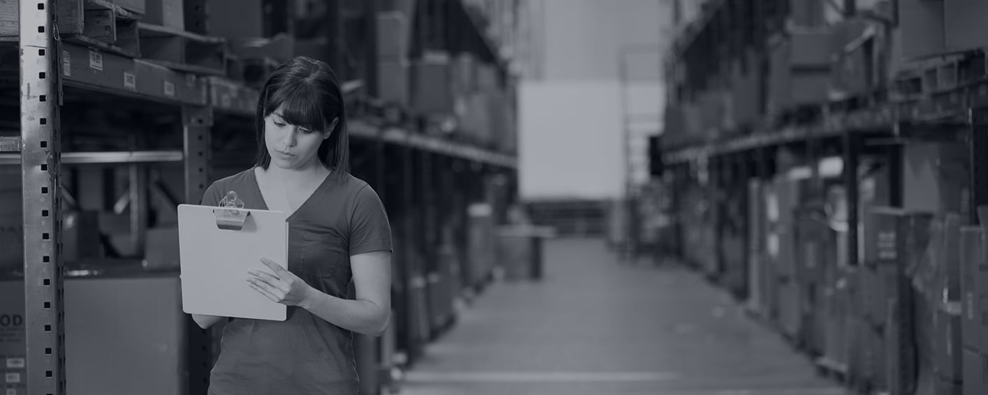 Woman completing an inventory of boxes in a warehouse